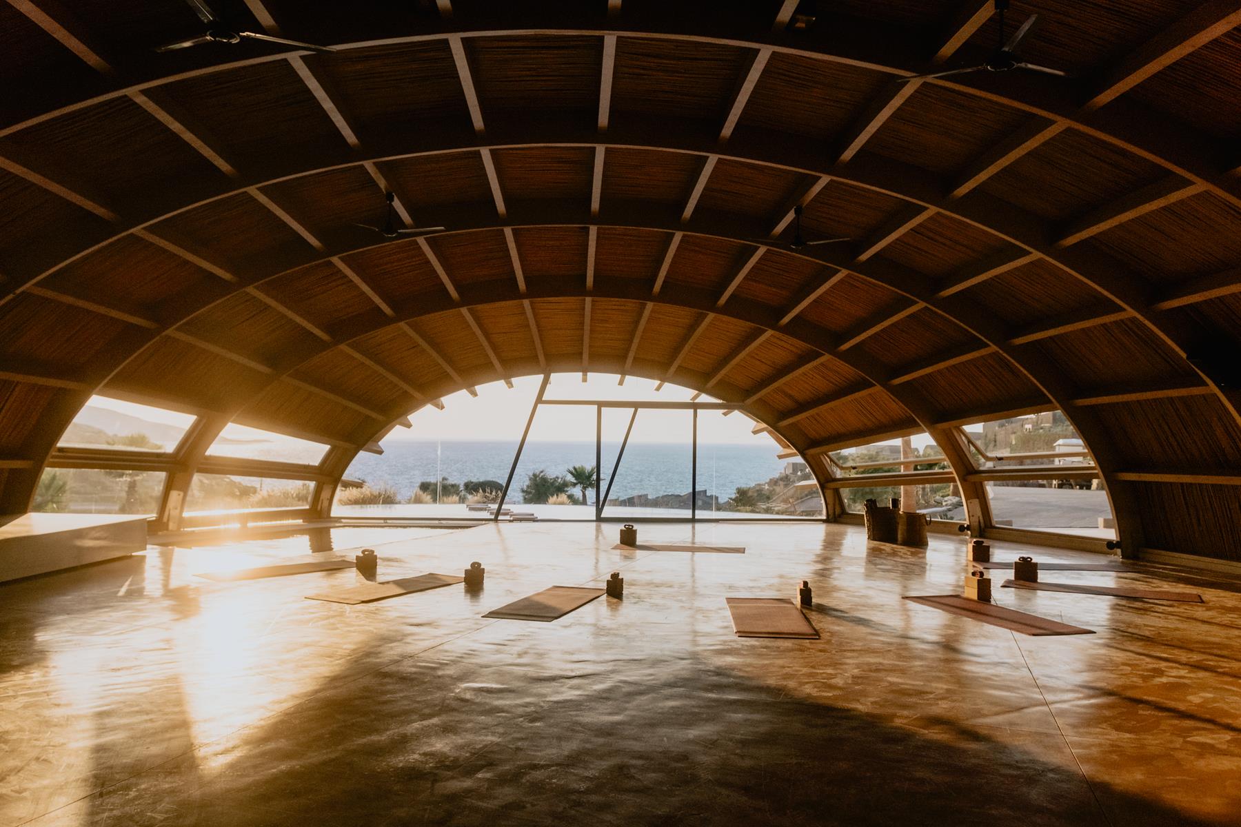The curved wooden Asana Fitness Club overlooking the sea at sunset