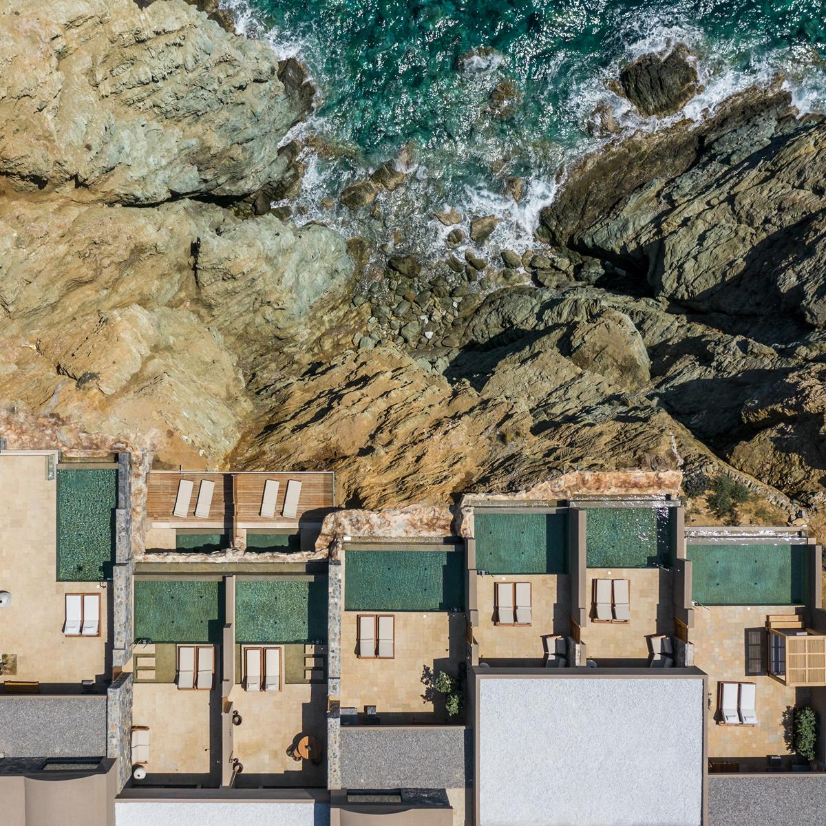 Aerial view of Acro Suites' private pools beside the rocky coastline