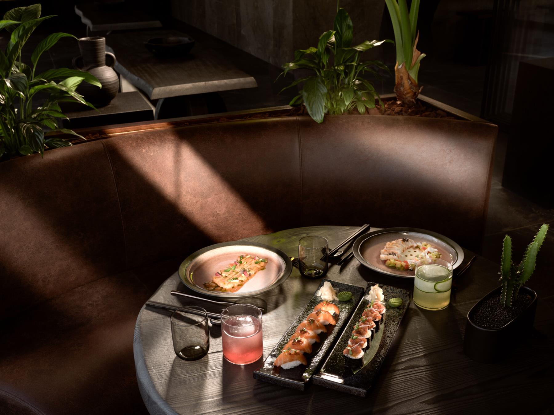 Umi Nikkei restaurant at Seaside, sushi and Nikkei plates on a dark timber table in low evening light