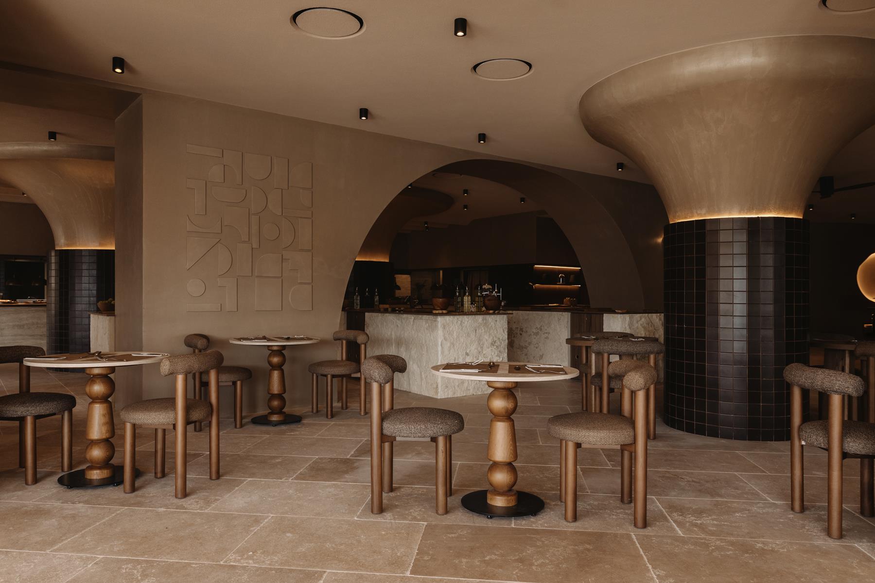 The Veranda restaurant at Seaside, sculpted arches, dark tiled columns and wooden tables set for dinner