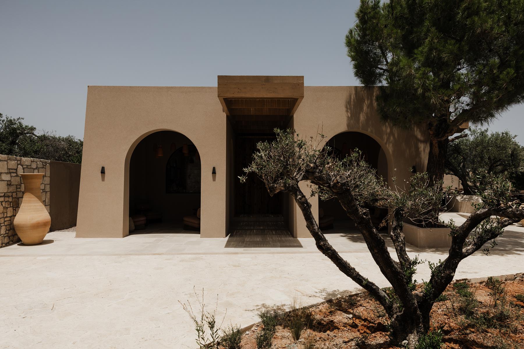 Momi Slow Living Hotel's arched entrance and olive tree courtyard
